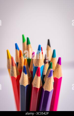A bunch of colored pencils are lined up in a row. The pencils are of different colors and sizes, and they are all sharpened. Concept of creativity and Stock Photo