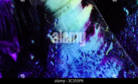 Abstract image of wet glass surface with vivid cyan, purple, and magenta smears and reflections, featuring light streaks and surface scratches. Stock Photo
