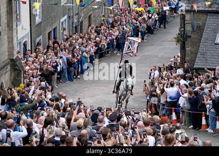 Langholm, UK. 25th July, 2025. Carrying the TownÕs Standard Cornet Ewan Alexander Patterson gallops up the Kirk Wynd during Langholm Common Riding on July 25, 2025 in Langholm, Scotland. A common riding is an equestrian tradition that mainly takes place in the Scottish Borders in Scotland where men and women ride out of the town and along its borders to commemorate the practices from the 13th and 15th centuries when there were frequent raids on the Anglo-Scottish border known as the Border Reivers. In Langholm this event dates back to 1759. ( Credit: Rob Gray/Alamy Live News Stock Photo