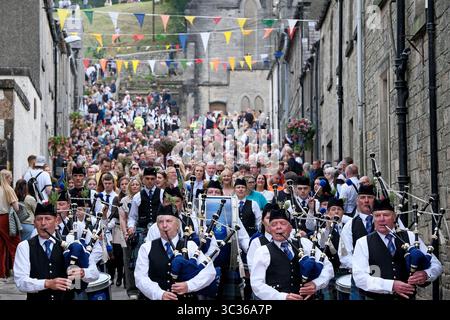 Langholm, UK. 25th July, 2025. The Pipe Band plays and leads the parade making their way through the streets during the towns common riding on July 25, 2025 in Langholm, Scotland. A common riding is an equestrian tradition that mainly takes place in the Scottish Borders in Scotland where men and women ride out of the town and along its borders to commemorate the practices from the 13th and 15th centuries when there were frequent raids on the Anglo-Scottish border known as the Border Reivers. In Langholm this event dates back to 1759. ( Credit: Rob Gray/Alamy Live News Stock Photo