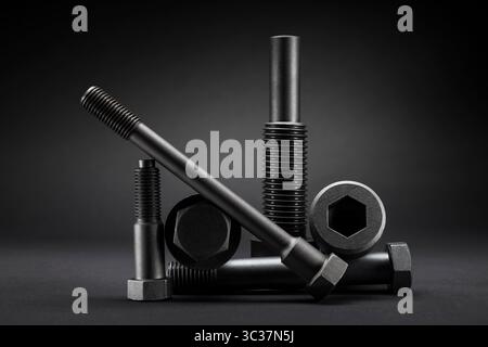 Variety of large black steel screws on black background. Stock Photo