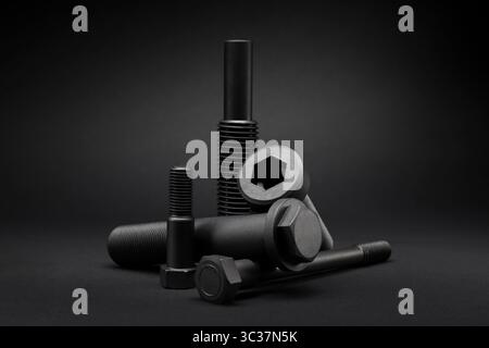 Variety of large black steel screws on black background. Stock Photo