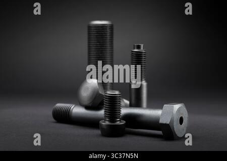 Variety of large black steel screws on black background. Stock Photo