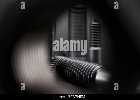 Variety of large black steel screws on black background. Stock Photo