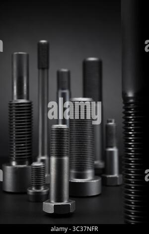 Variety of large black steel screws on black background. Stock Photo