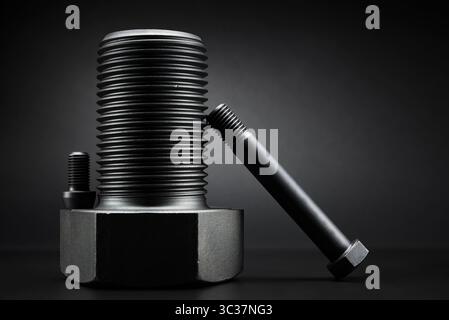 Variety of large black steel screws on black background. Stock Photo
