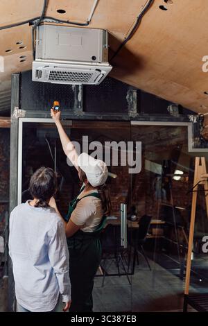Women checking air conditioning units after installing indoors Stock Photo