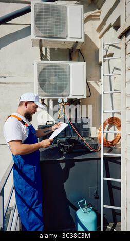 Technician inspecting rooftop air conditioning system with tools and equipment Stock Photo