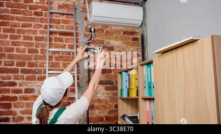 Technician installs and taking a picture of air conditioning unit in office space. Stock Photo