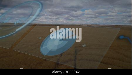 Displaying translucent circular radar panel over rural farmland, with grid panels and overlay icons Stock Photo