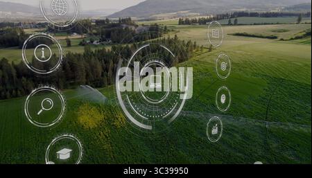 Displaying interface with laptop icon hovering over farmland, with irrigation sprinklers Stock Photo