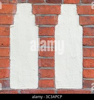 A close-up architectural shot showing two vertically elongated plaster inlays within a red brick wall. Stock Photo