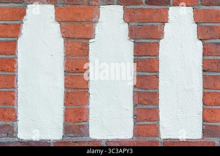 White bottle-shaped silhouettes painted on a red brick wall. Repetitive pattern and the textured contrast between paint and masonry. Stock Photo