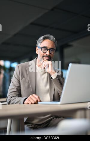 Smiling mature business man entrepreneur using laptop working outside office. Stock Photo