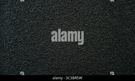 Close-up view of a dark, grainy surface providing a textured, uniform backdrop, ideal for various graphic design applications Stock Photo