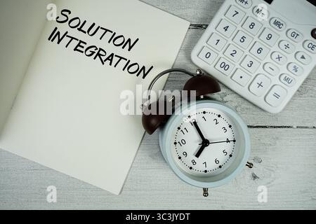 Solution Integration text on paper notebook page with alarm clock and calculator on wooden background Stock Photo