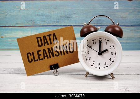 Data Cleansing text written on paper card with alarm clock on wooden background Stock Photo