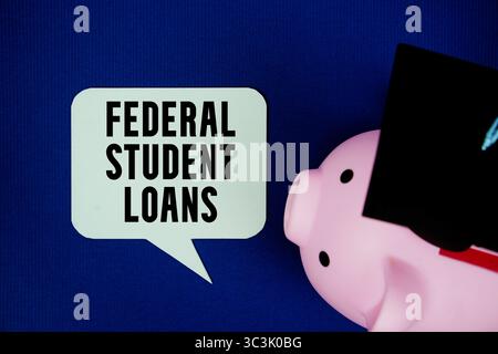 Federal Student Loans text on speech bubble with piggy bank and graduation cap top view on navy blue background Stock Photo