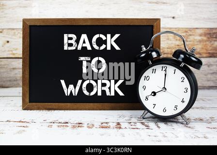 Back To Work text message and alarm clock on wooden background Stock Photo