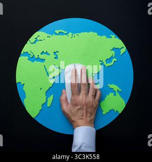 An overhead shot of a hand operating a computer mouse on a map of the Earth. Global connectivity, digital interaction, technology concept. Stock Photo