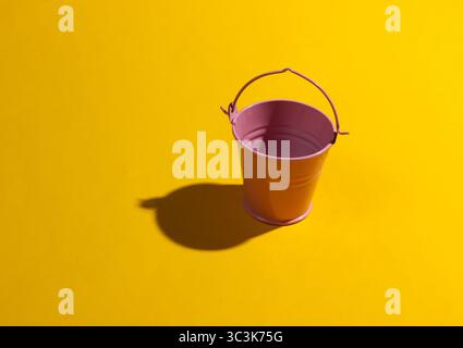 Empty mini pink bucket on a yellow background. Studio shot with shadow Stock Photo