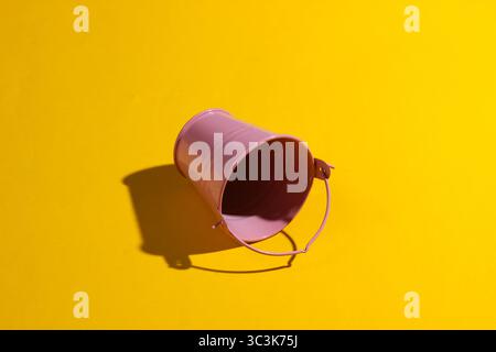 Empty mini pink bucket on a yellow background. Studio shot with shadow Stock Photo