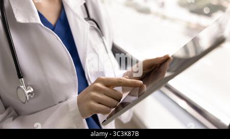 Young female doctor using tablet pc, touching screen with finger Stock Photo