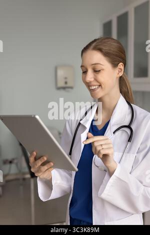 Positive young 20s general practitioner woman using tablet Stock Photo