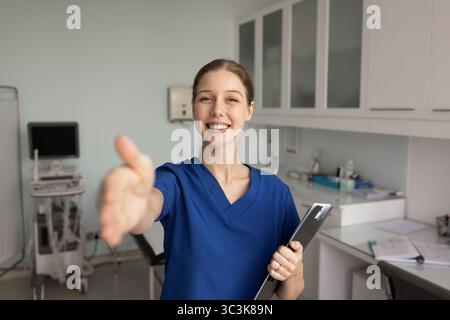 Happy beautiful young practitioner woman giving handshake at camera Stock Photo