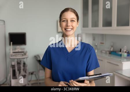 Positive ultrasound diagnosing doctor in blue scrubs posing in office Stock Photo