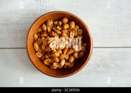 A top down view of roasted peanuts in a clay bowl. Stock Photo