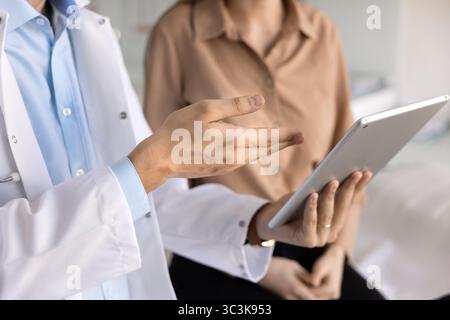 Male doctor using digital tablet, giving consultation to patient Stock Photo