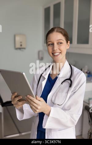 Positive female doctor using digital tablet for analyzing medical data Stock Photo