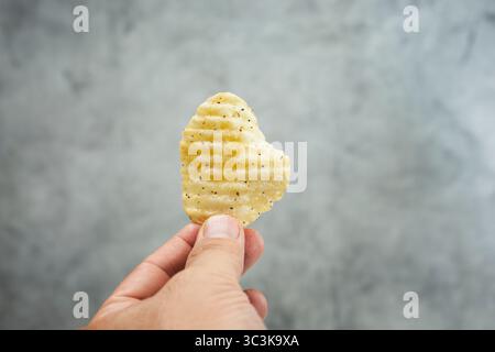 A view of a hand holding a single ridged potato chip. Stock Photo