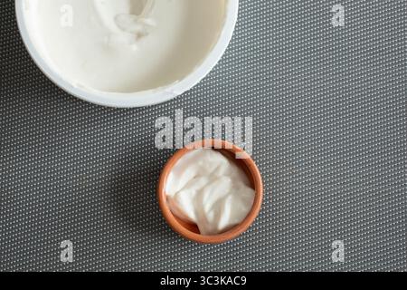 A top down view of dairy-free sour cream in its package and in a clay condiment cup. Stock Photo
