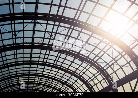 Glass dome ceiling with metal grid. Architectural structure with curved beams and sunlight. Modern urban roof design. Abstract construction background Stock Photo