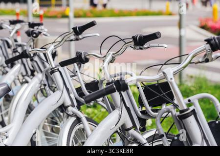City rental bikes on street. Public bicycle sharing system in urban environment. Eco transport concept. Parked bikes in row. Green commuting option. Stock Photo