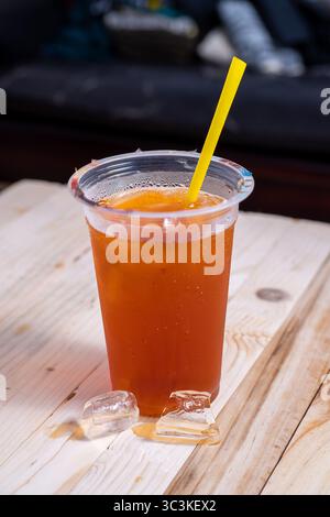 Iced tea in a clear plastic cup with yellow straw. Fresh, cold, and sweet drink perfect for summer, street food, or refreshment visuals Stock Photo