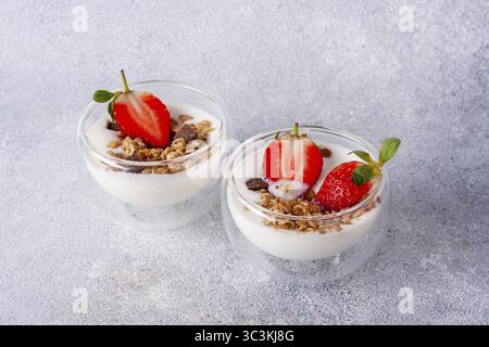 Two glass cups with muesli, kefir, strawberries Stock Photo