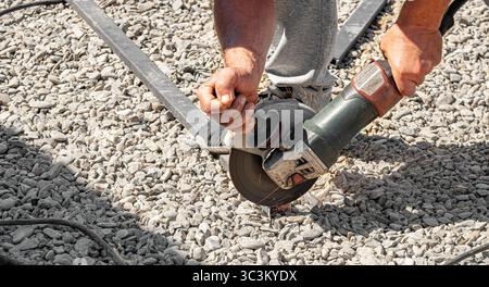 Close-up of a construction worker using an angle grinder to cut metal Stock Photo
