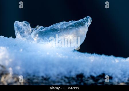 Broken frozen soap bubble on snow and dark background Stock Photo