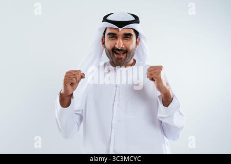Middle-eastern doctor wearing emirati kandura working in the office - emirati businessman in traditional kandura celebrating a successful deal in a br Stock Photo