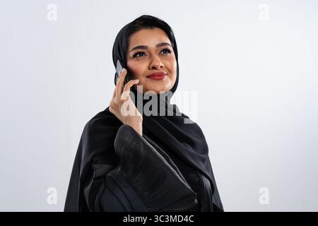 Elegant businesswoman wearing traditional arab clothing using smartphone, representing modern communication and female empowerment in the middle east Stock Photo