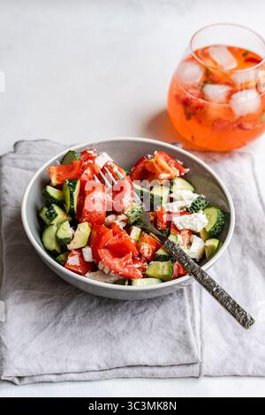 Enjoy a refreshing summer salad featuring crisp cucumbers, juicy tomatoes, and creamy feta cheese. Perfect for a light and healthy lunch under the war Stock Photo