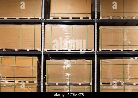 Shelves packed with stacked and wrapped cardboard boxes containing solar panels in an organized and efficient industrial warehouse setting, ready for Stock Photo