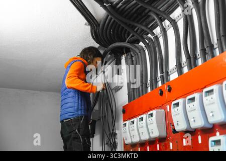 A technician is organizing and managing cables during the solar panel installation process. The workspace shows electrical meters and extensive cablin Stock Photo