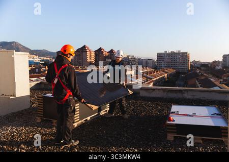 Engineers working together on a rooftop to install solar panels. They are strategically placing the panels to maximize energy efficiency, showcasing t Stock Photo