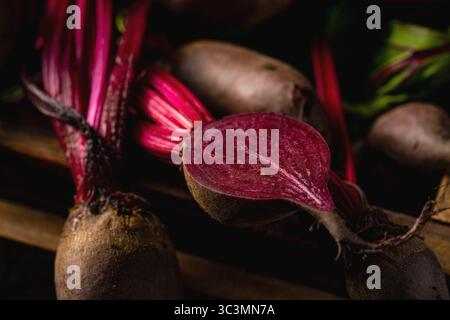 From above fresh beetroots with vibrant red stems and lush green leaves are captured in a close-up shot, highlighting their natural textures and earth Stock Photo