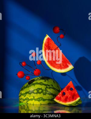 A creative display of watermelon slices and small watermelon balls artfully arranged against a striking blue background, highlighting vibrant reds and Stock Photo
