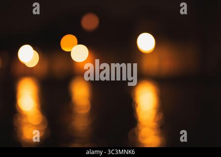 A mesmerizing abstract image of golden bokeh lights softly reflecting on a dark surface, creating a magical and serene atmosphere with warm and soothi Stock Photo